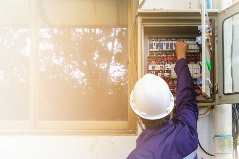 En elektriker jobbar med kablar utanför ett hus.